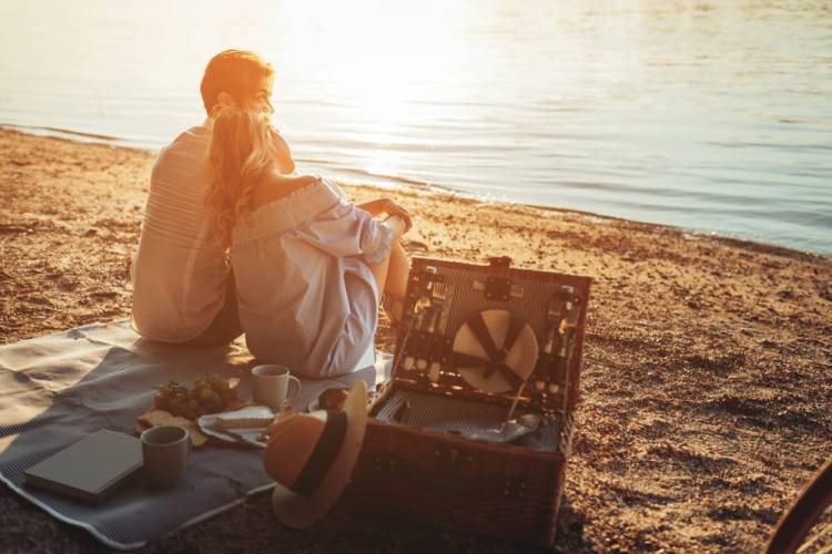 A couple on a picnic on the beach at sunset