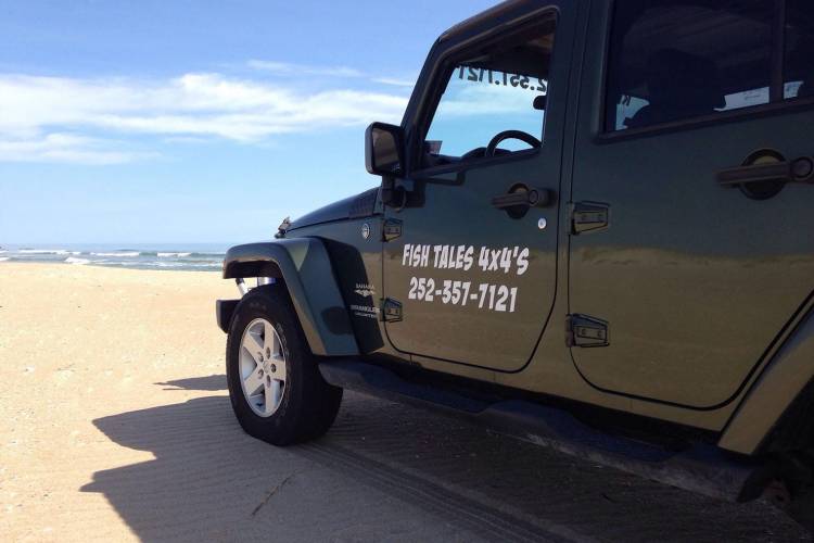 A black Jeep on a sandy beach 