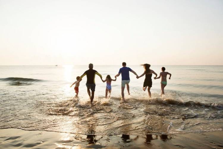 family running into the surf at sunset