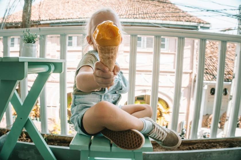 little kid holding ice cream cone in front of their face